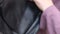 Black leather backpack. A woman reviews a backpack. Close-up. Vertical video