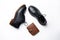 Black leather derby shoes with polyurethane soles and a brown purse with a button on a white background