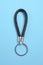 Black leather keychain on light blue background, top view