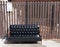 Black leather sofa and wooden armrest chair with white mailbox on brown background.