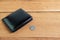 Black leather wallet with 5 baht coins on wooden floor