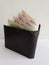 black leather wallet with singaporean banknotes and white background