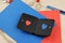 Black leather wallet with two paper valentine hearts red and blue on craft desktop with color papers knife and rope