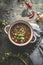 Black lentil soup in soup bowl on dark table background with spoon. Healthy vegetarian or vegan food concept. Top view