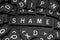 Black letter tiles spelling the word & x22;shame& x22;