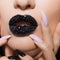 Black lips covered with rhinestones. Beautiful woman with Black lipstick on her lips and black and white manicure