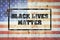 Black Lives Matters. Stamp on the background of the flag of America on a concrete wall. Equal rights of citizens. Conflicts