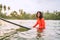 Black long-haired teen man floating on long surfboard, waiting for a wave ready for surfing with palm grove litted sunset rays.