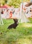 A black longhaired Chihuahua dog performs a trick at a competition and sits on the grass.