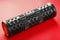 Black lumpy foam massage roller on red background. For the mechanical and reflex effects on tissues and organs