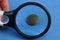 Black magnifier enlarges old green brass button