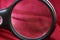 Black magnifier enlarges a piece of red cloth