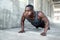 Black male working out alone outside on concrete, pushups in urban downtown city exercise