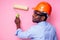 Black man African American holding paint roller in hand paints the wall in pink color .happy african builder painting