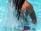 Black man with afro hair and dreadlocks comes out of the pool splashing water
