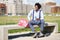 Black man with afro hair taking a coffee break sitting on a park bench.