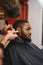 Black man in the barbershop. Cute black man makes a haircut in the African salon. Hair style. Haircut for adults