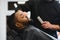 Black man in the barbershop. Cute black man makes a haircut in the African salon. Hair style. Haircut for adults