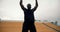 A Black man in black sportswear doing a burpee exercise in a stadium with yellow stands