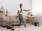 Black man cleaning floor with vacuum cleaner and mop