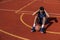 Black man doing sit ups and crunches exercising abdominal muscles outdoor on basketball court.