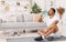 Black Man Drinking Water During Workout Sitting On Mat Indoors