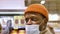 Black man in hat and face mask walks along grocery store