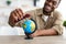 Black Man Playing With Train Model And Globe At Home