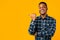 Black Man Pointing Thumb Aside Posing Over Yellow Studio Background