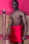 Black man posing near a reed screen