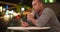 Black man sitting alone at outdoor cafZ drinking coffee at night and browsing the internet on smartphone