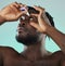 Black man, studio and eye drop for health vision, wellness and self care by blue backdrop for morning routine. African