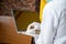 Black man wearing a lab coat and face mask and shield cleaning his laptop computer surface