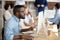 Black manager holding pen make notes on textbook using pc