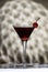 Black Manhattan cocktail with whiskey and red vermouth garnished with maraschino cocktail cherry in martini glass. Beige