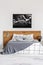 Black map on white wall above wooden headboard in simple bedroom interior