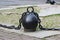 Black metal chain with large links and round heavy weights lies on concrete slabs on the ground.