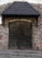 Black metal door is under a canopy in old stone wall