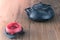 Black metal Japanese tea pot on a wooden table with red candle. Zen-style still life in warm, peaceful colors. Hot tea