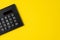 Black minimal calculator on solid yellow background with copy space using for financial activity, accounting, tax calculation or