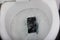 Black mobile phone falling into toilet flushing