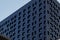 Black modern ventilated facade with windows. Fragment of a new elite residential building or commercial complex. Part of urban