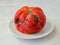 Black mold on a spoiled red tomato. Rotten tomato on a white plate over a rough white textural background. Spoiled fruits and