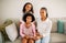 Black Mommy And Daughters Hugging Sitting On Sofa At Home