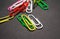 On black monophonic background plastic multi-colored paper clips   are lie. White, red, green, yellow colors. Office.