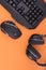 Black mouse, the keyboard, the headphones are isolated on a orange background, the top view