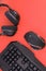 Black mouse, the keyboard, the headphones are isolated on a red background, the top view. Flat lay gamer background