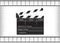 Black movie clapperboard and cine-film on gray background