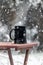 Black mug of hot steaming coffee, on a table outside in the snow. Winter wonderland