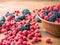 Black mulberries and red raspberries on brown table, close up view. Brown bowl full of red and black berries. Fruit